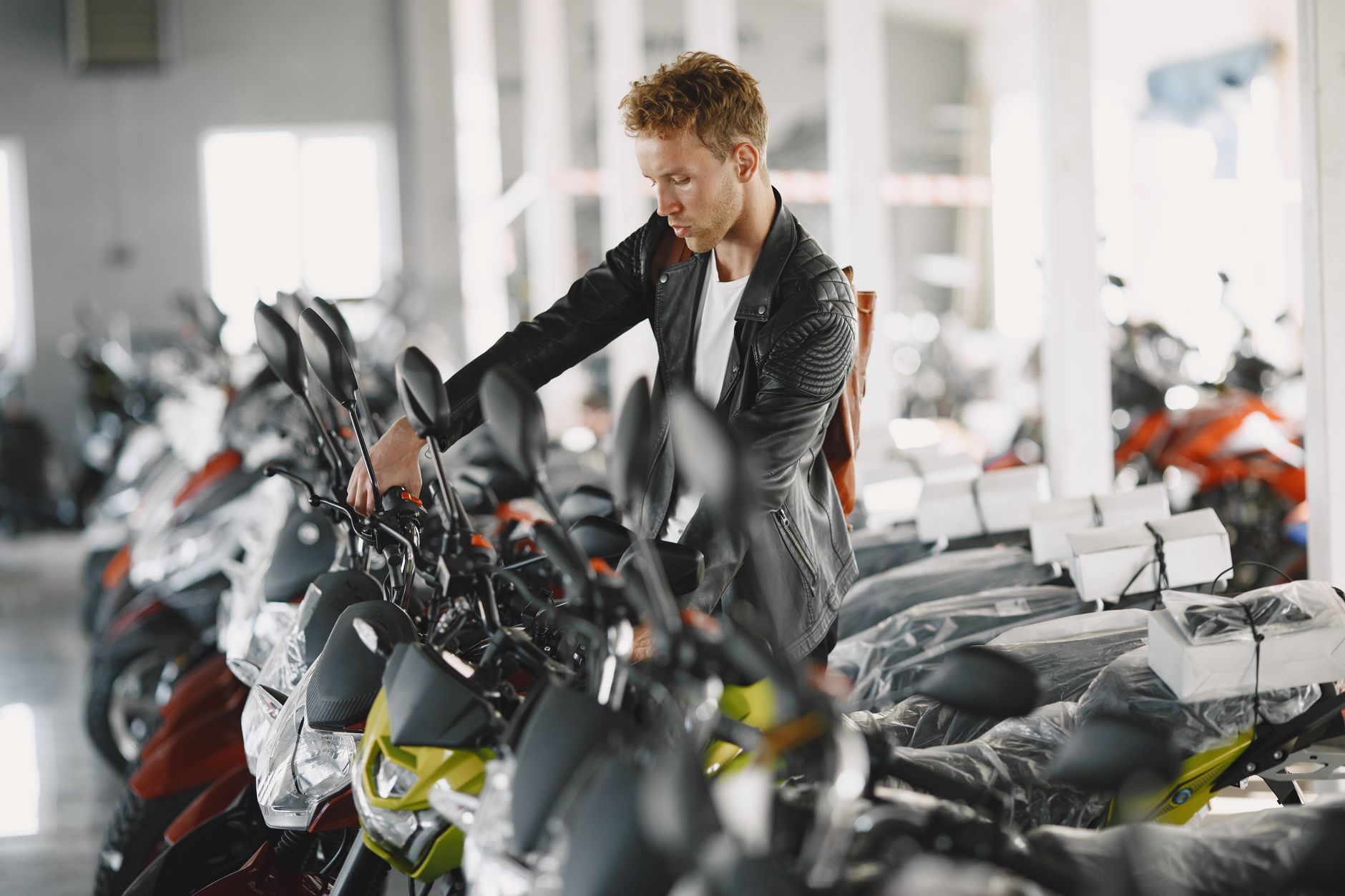 Man inspecting motorcycles indoors at a dealership showroom.