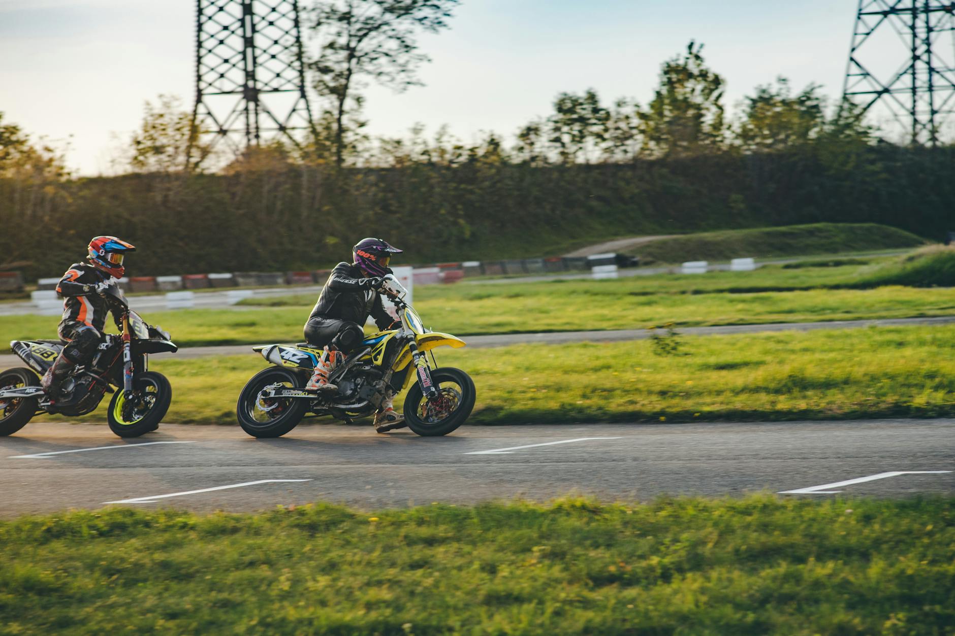 Two motorcyclists racing on an outdoor track, showcasing thrilling motor sport action.