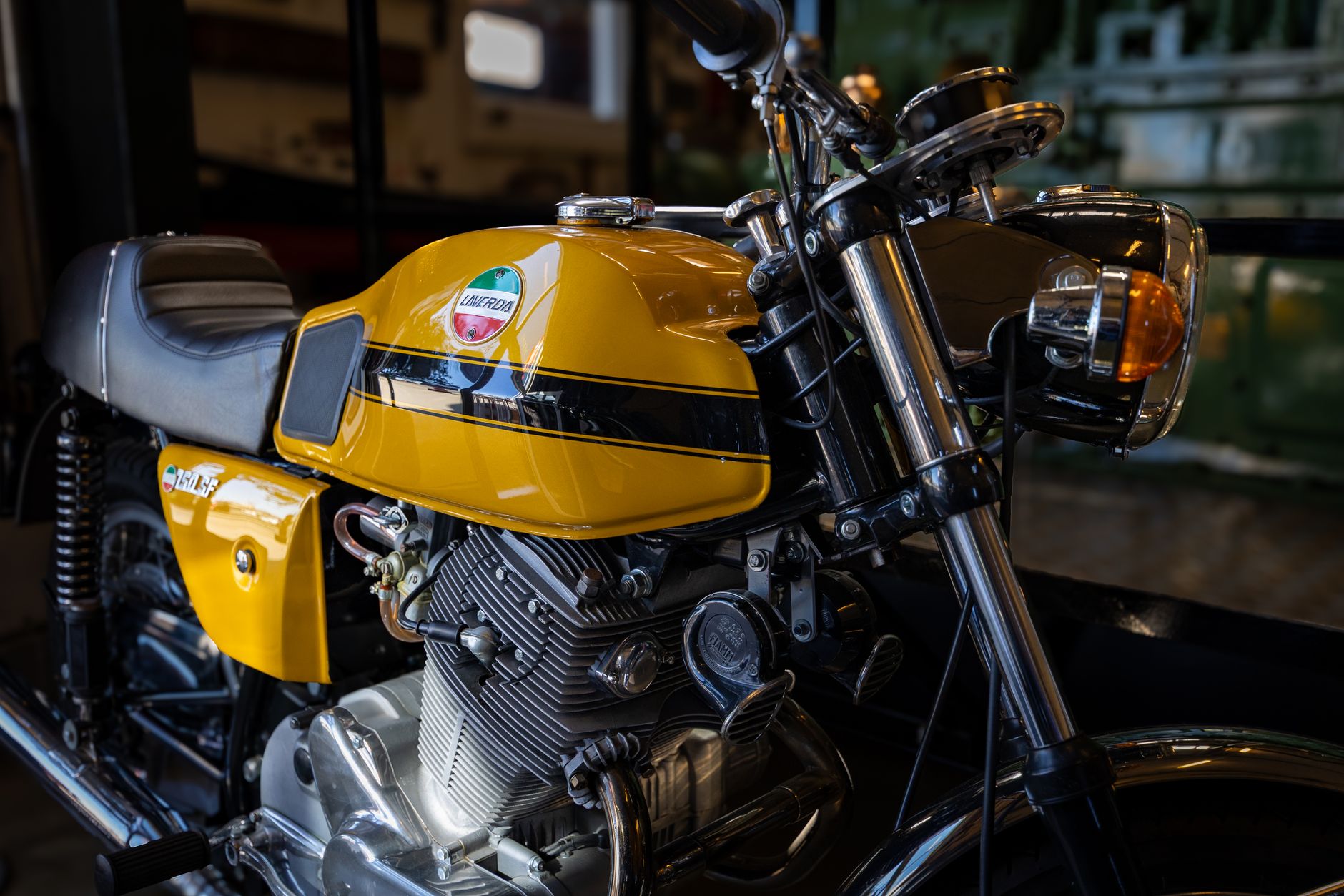 Close-up of a vintage yellow Laverda motorcycle indoors, showcasing its engine and design.