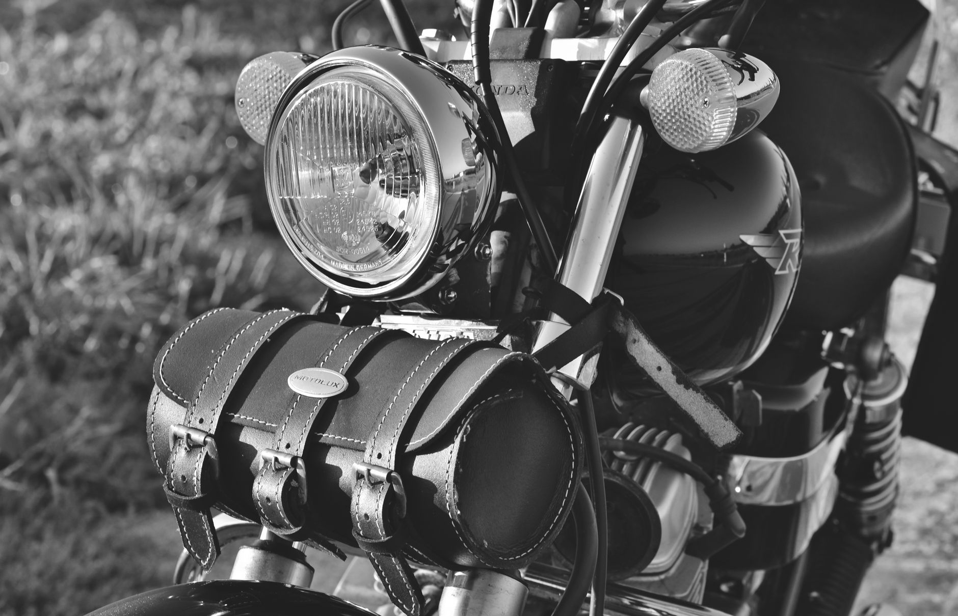 Black-and-white close-up of a classic vintage motorcycle with leather saddlebag.