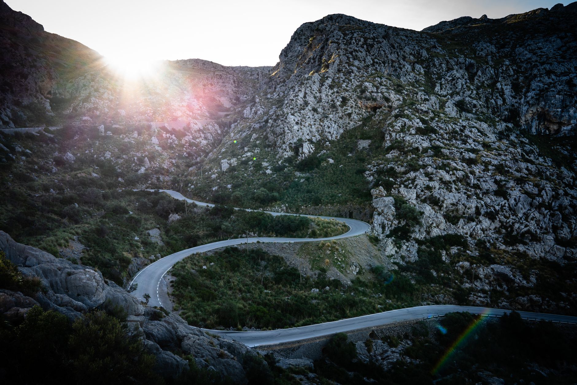 Winding mountain road with rocky landscape at sunrise, perfect for adventure seekers.
