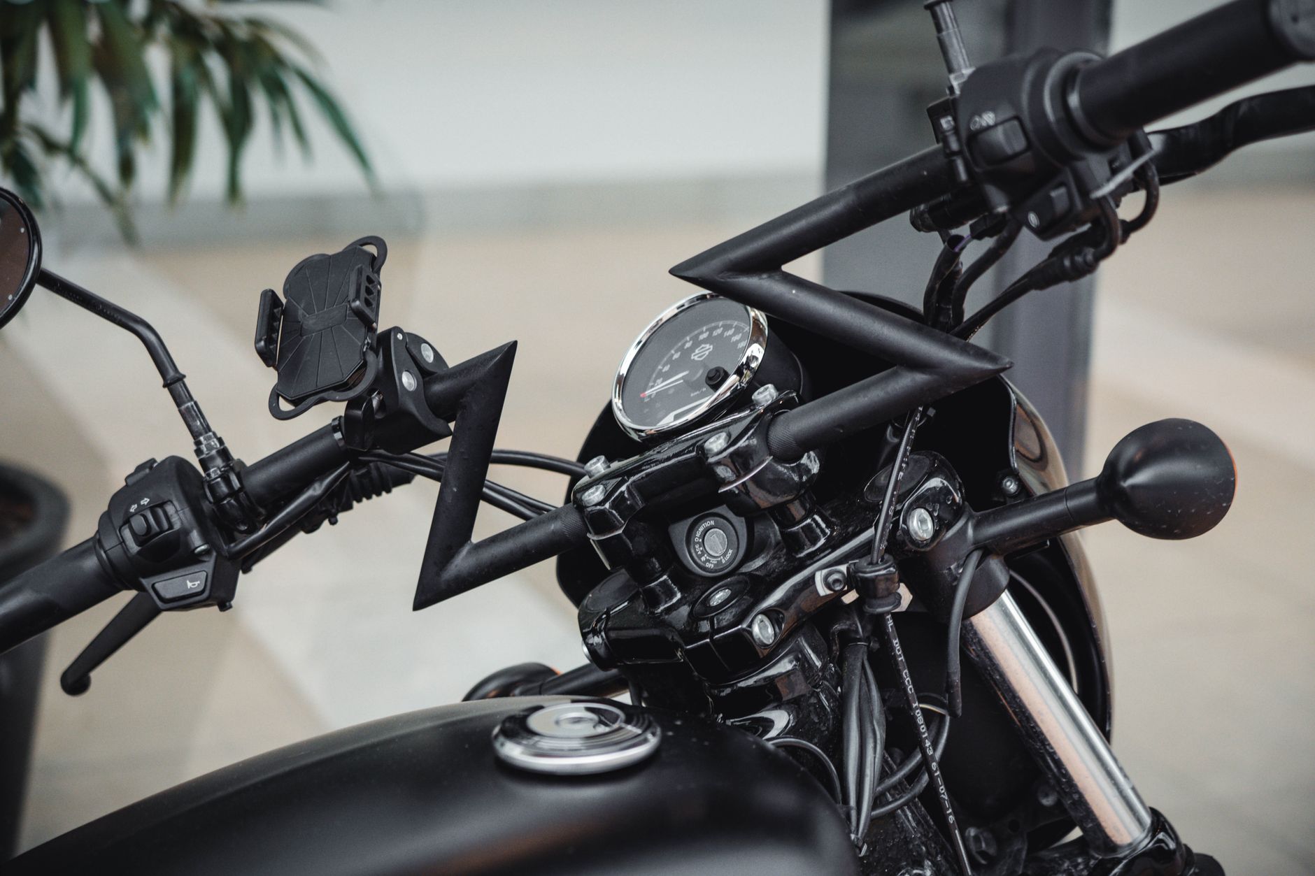 Detailed view of a black motorcycle's handlebars and gauges with modern design and accessories.