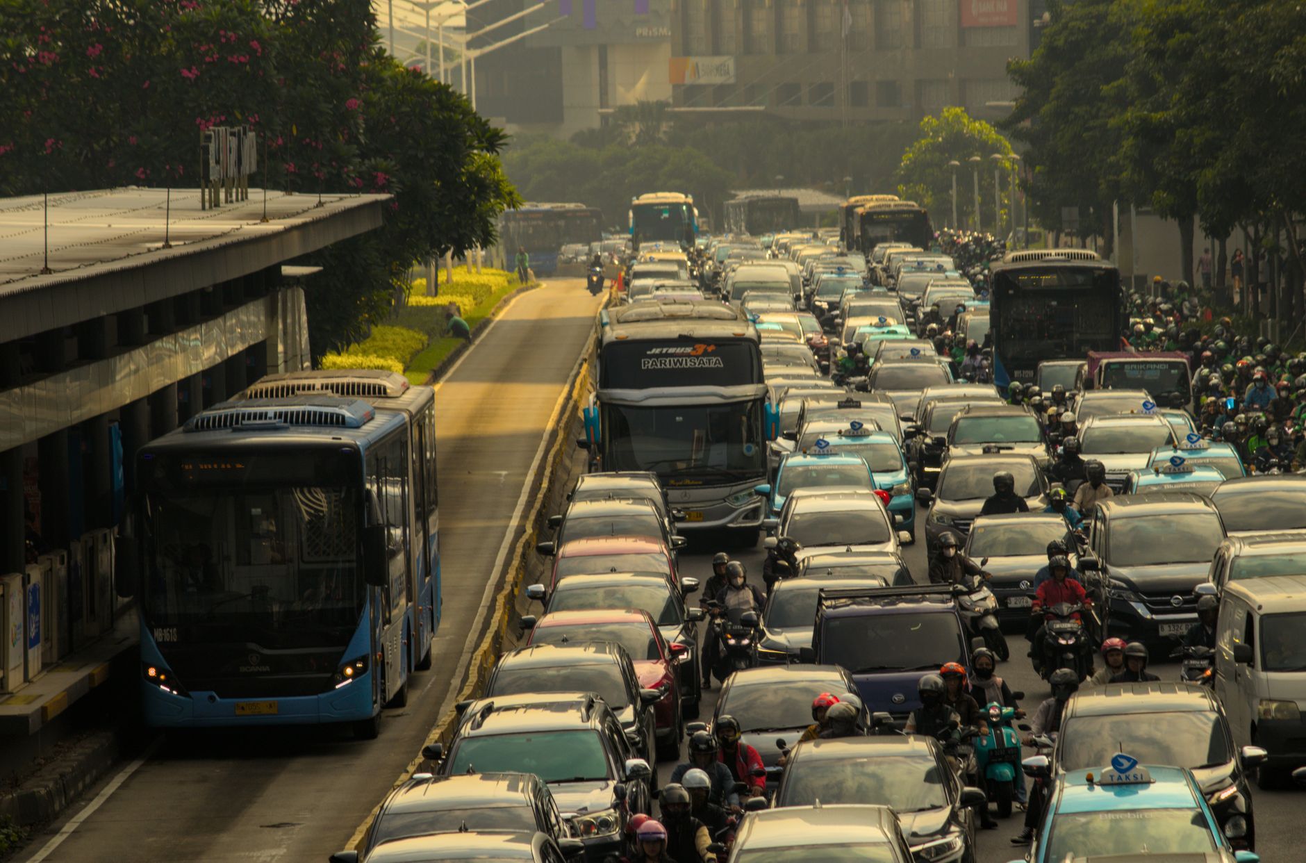 Heavy traffic in a city with cars, buses, and motorcycles on a crowded road.