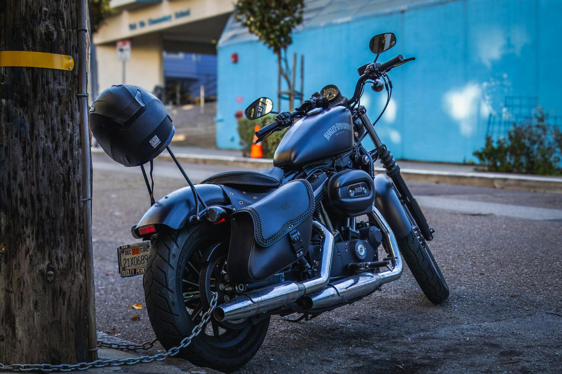 A classic Harley Davidson motorbike chained to a post on a city street, embodying urban lifestyle and adventure.