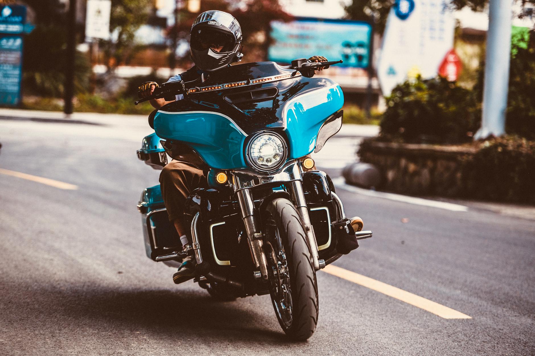 A man rides a blue motorcycle on urban streets, showcasing an adventurous lifestyle.