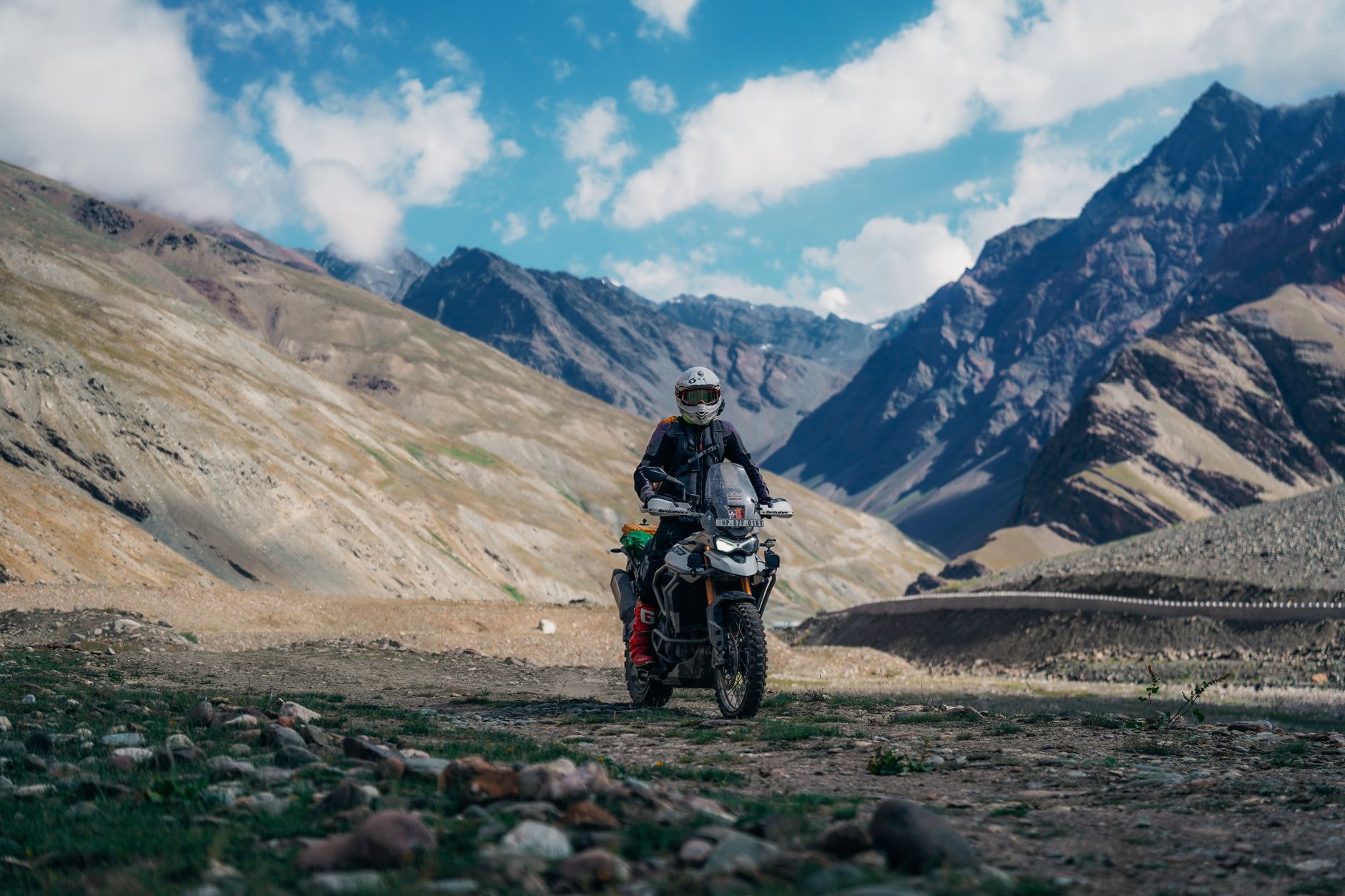 Adventure motorcyclist on rugged mountain terrain during daytime exploring scenic views.
