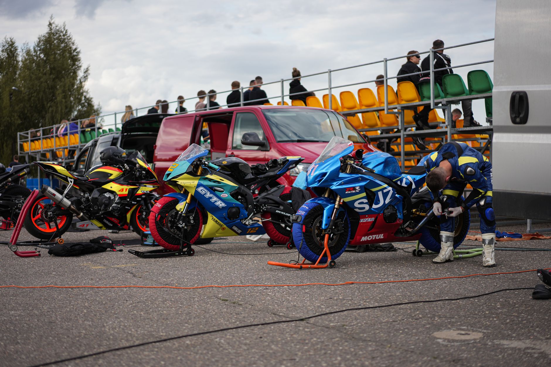 Racers prepping bikes for a motorsport event at an outdoor track.