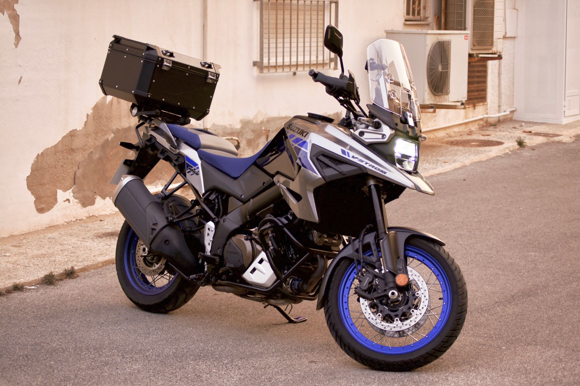Suzuki V-Strom adventure motorcycle parked on a sunlit street in La Zenia, Spain.