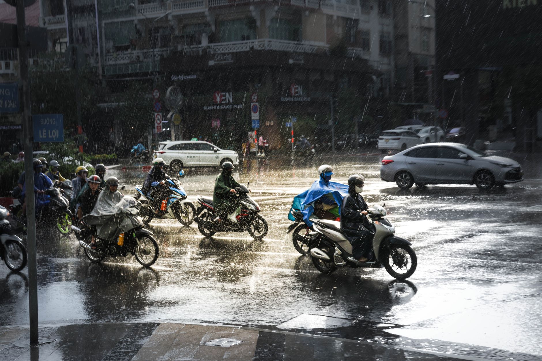 Motorcyclists navigate a rainy intersection in Ho Chi Minh City, showcasing urban resilience and mobility.