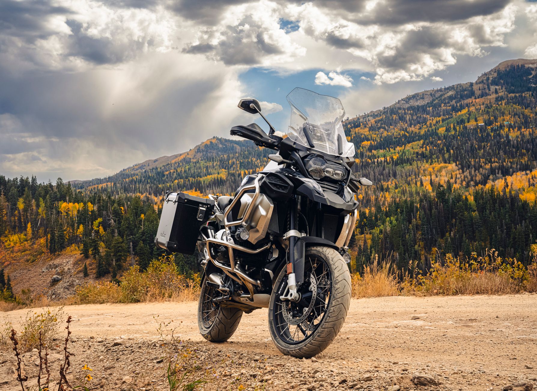 Powerful adventure motorcycle parked on a mountain road with autumn foliage.