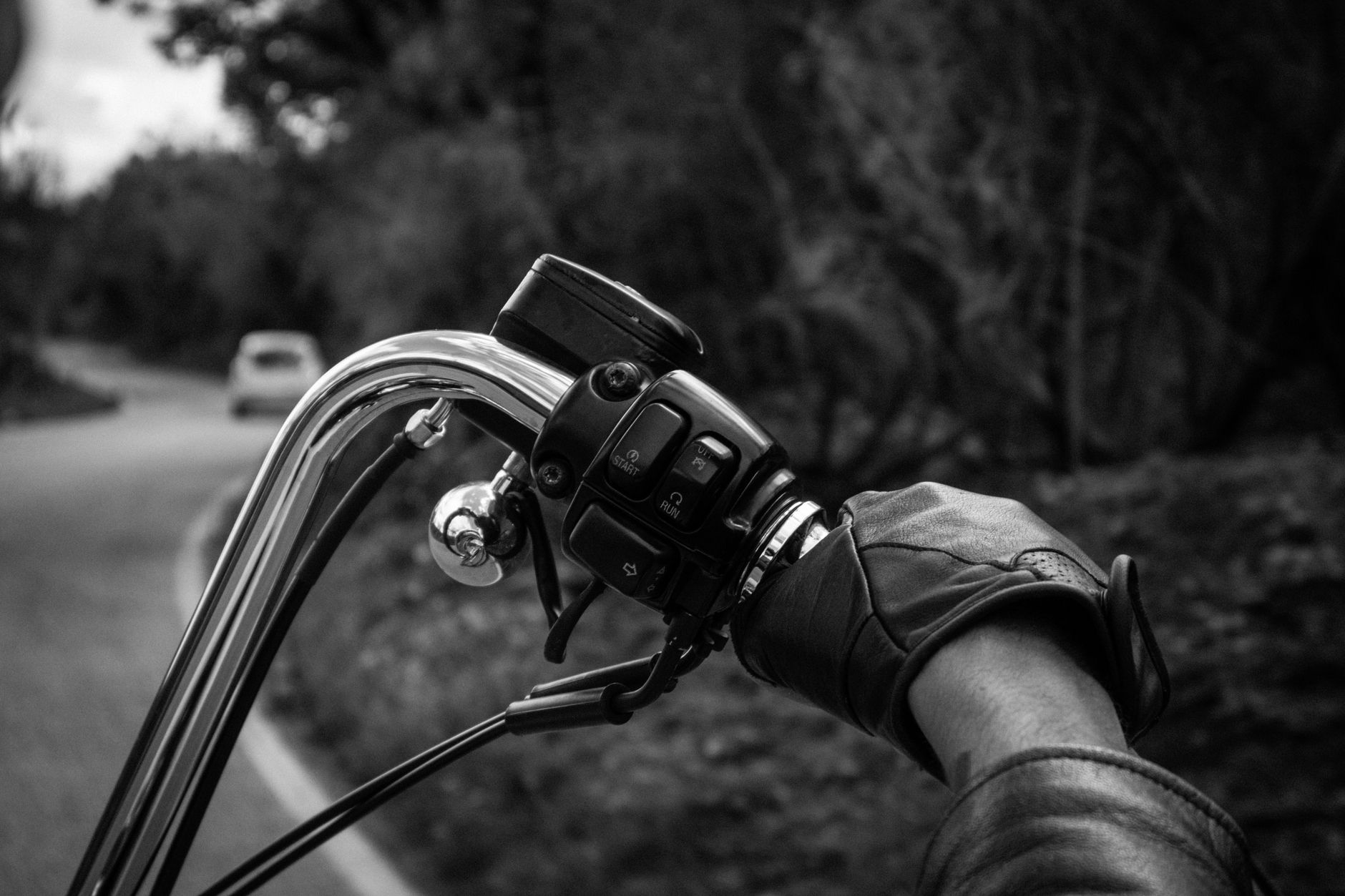 Black and white close-up of a motorcyclist riding on a winding road, showcasing the gripping journey.