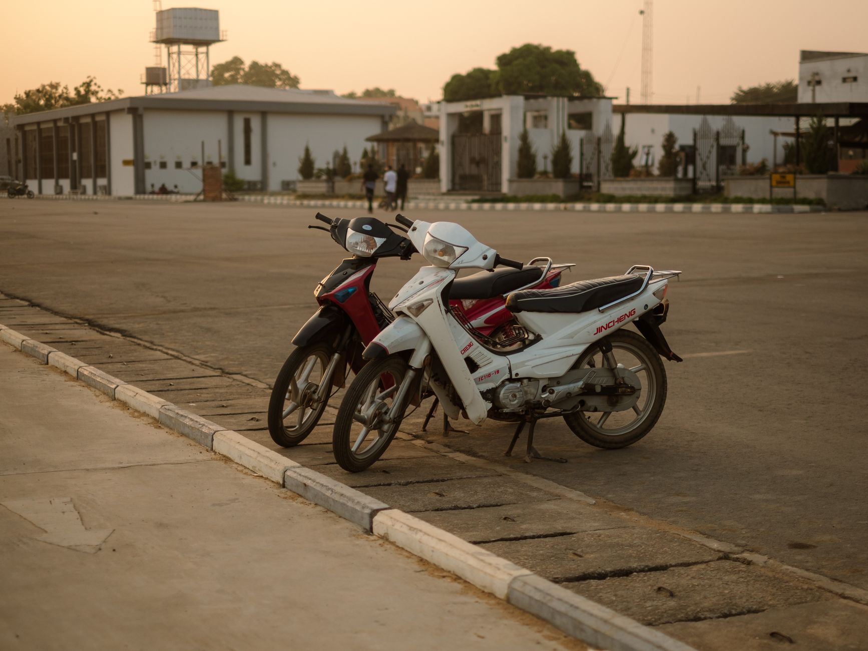 Two motorcycles parked in an urban setting at sunset, offering a serene and warm ambiance.